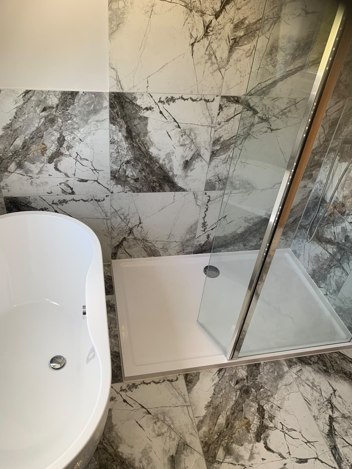 Marble tiled bathroom with freestanding bath and walk-in shower